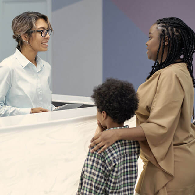 a woman and young son talking to a business owner at a reception desk