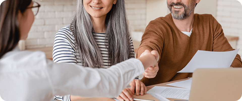 Two business owners and a sales representative shaking hands on a contract for google review management services