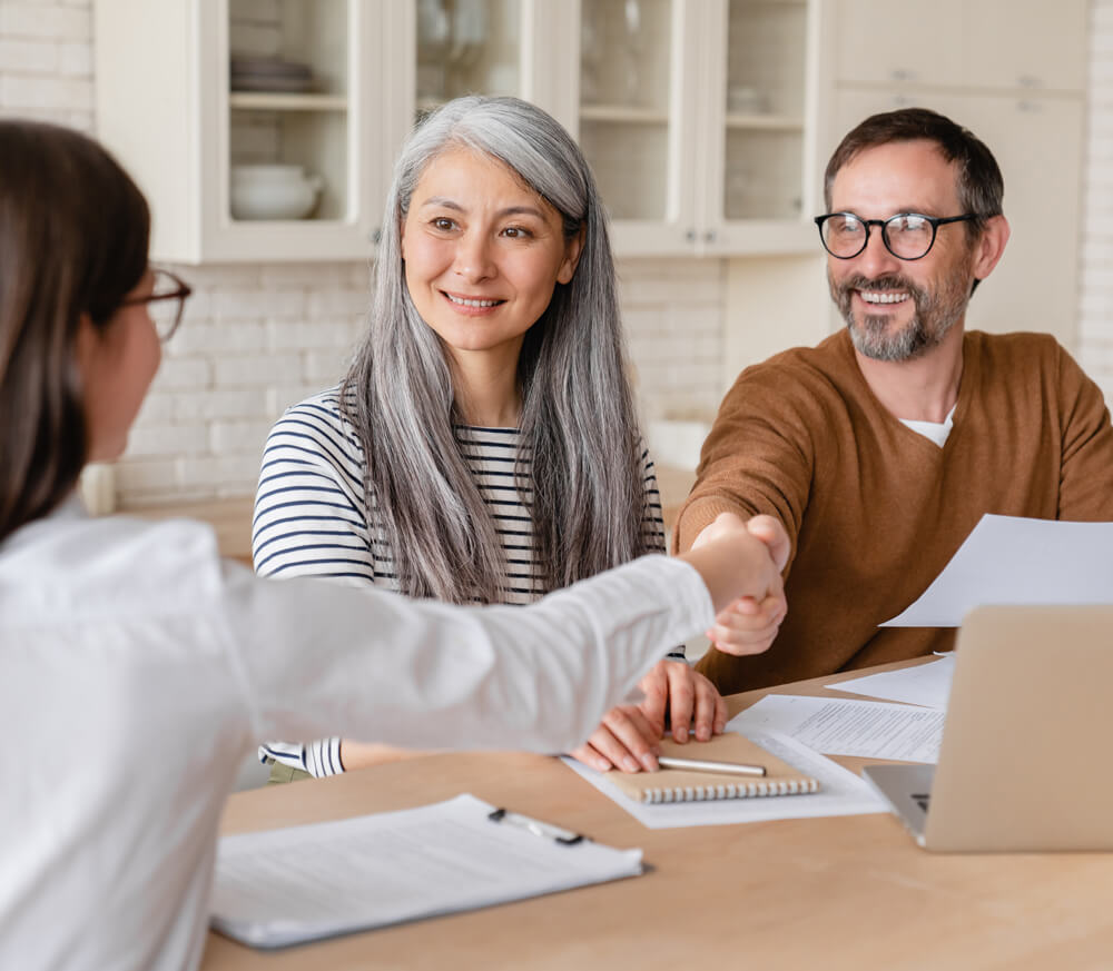 Two business owners and a sales representative shaking hands on a contract for reputation management software